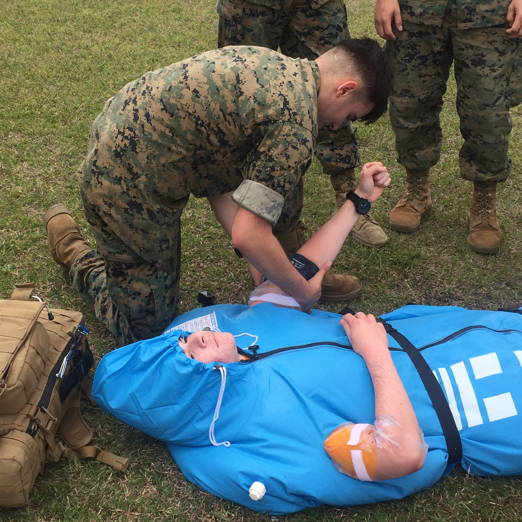 Soldier kneeling over man in polar life pod cold water immersion device